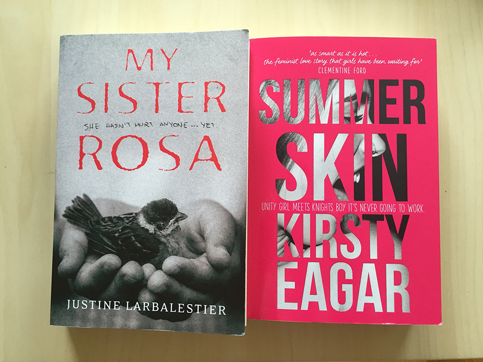 photo of two books on a wooden table: My Sister Rosa by Justine Larbalestier and Summer Skin by Kirsty Eagar